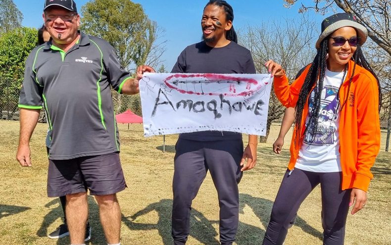 3 colleagues hold up their team banner for Ground Zero bush games