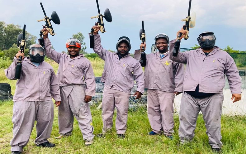 A group of friends dressed in paintball gear 