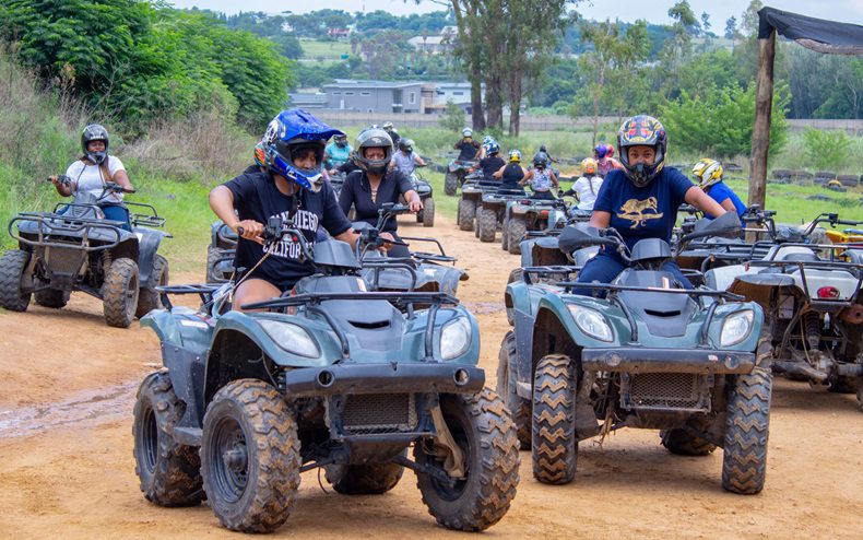 A group of friends quad biking on a dirt road