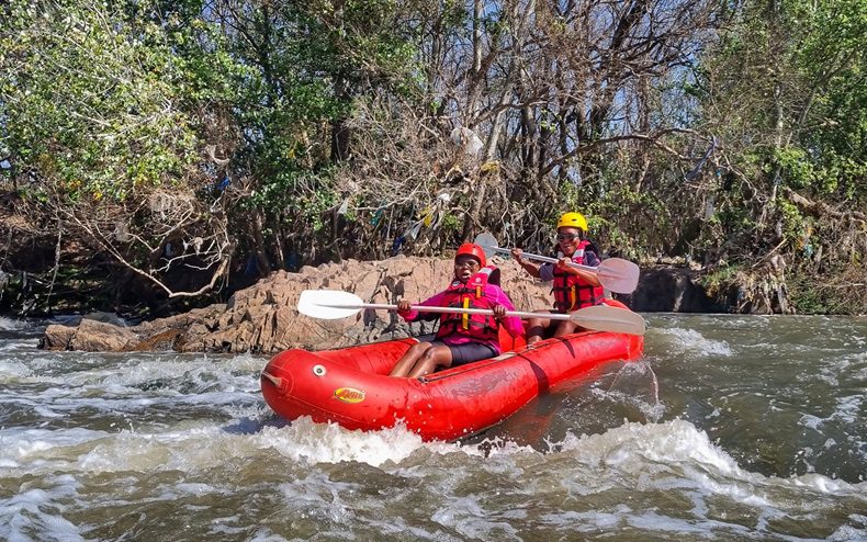 Two friends paddle in a river raft