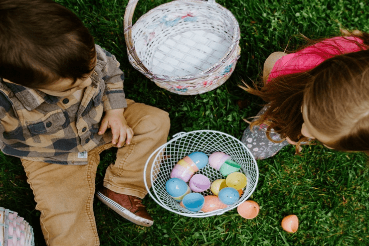 Kids sitting on the grass and playing with plastic Easter eggs that they collected on their Easter Egg Hunts