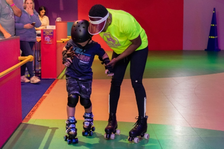 A child being taught how to roller skate by a guide