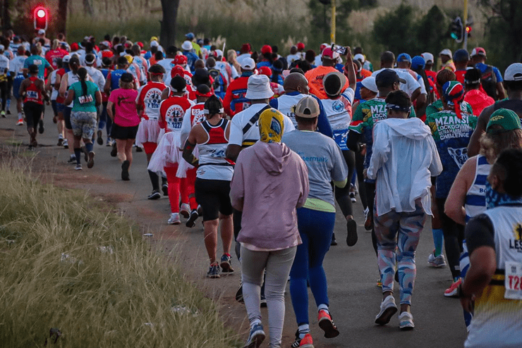 A large group of runners running with their backs towards the camera