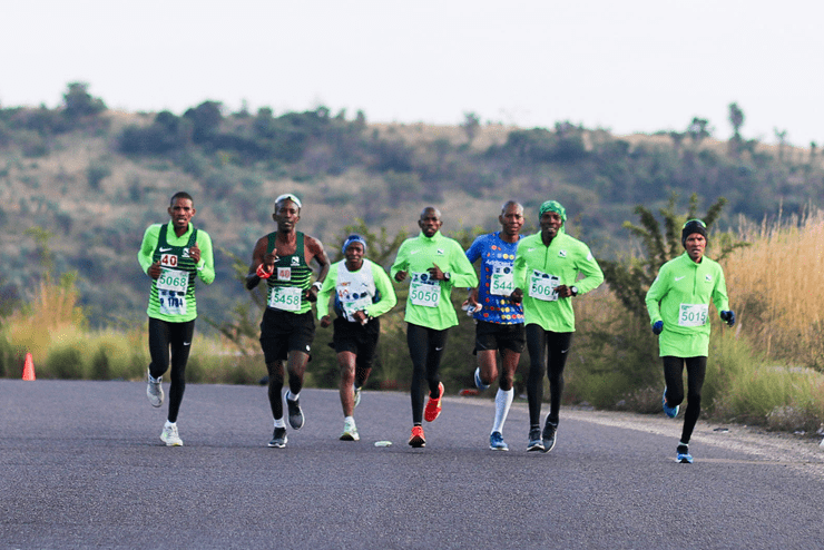 A group of seven runners running on the road in a horizontal line