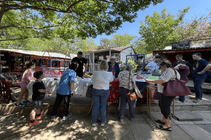 Market attendees look at products at a stall - June events