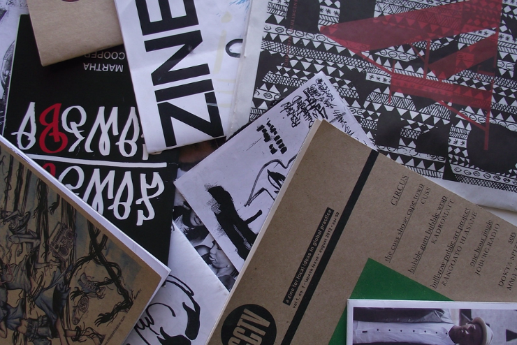 A collection of zines laying disorganised on top of on another - July Events