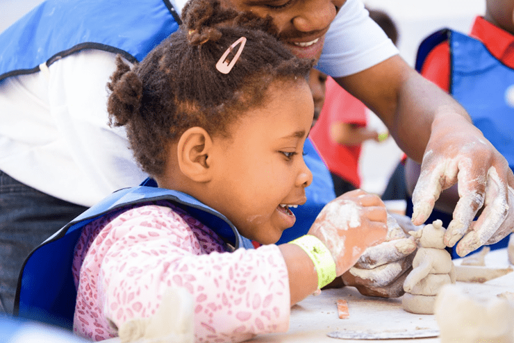 A father and daughter play with clay