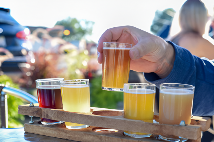 A tray of tasting glasses filled with various beers - July events