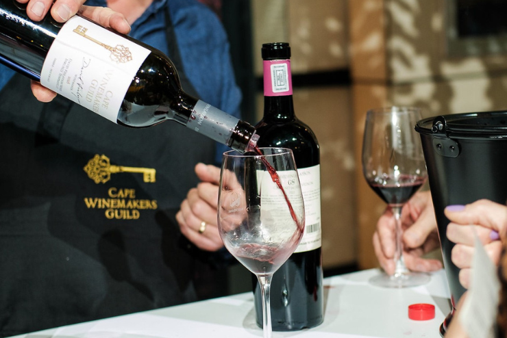 A hand pouring red wine into a glass